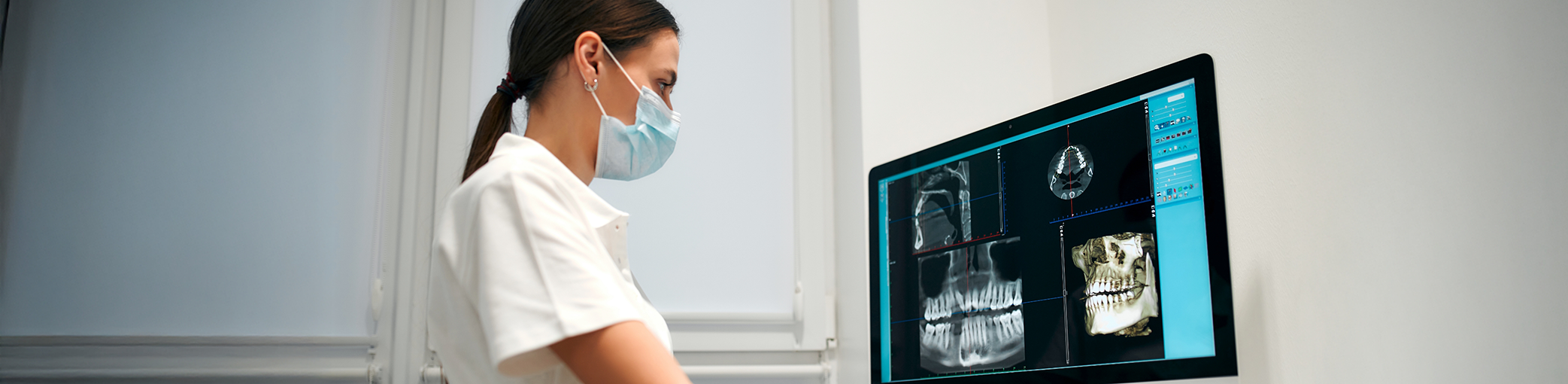 Dentist looking at x rays of teeth on a computer monitor