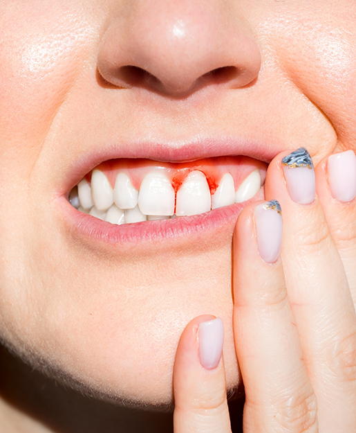 Person with red spots in their gums holding their cheek in pain