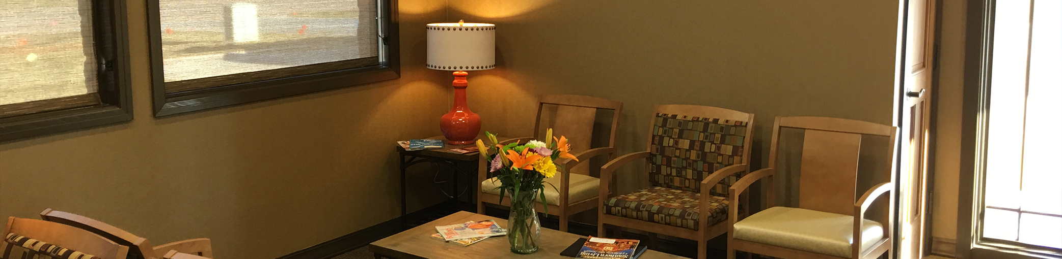 Lamp on an end table between chairs in waiting area of Bullard dental office