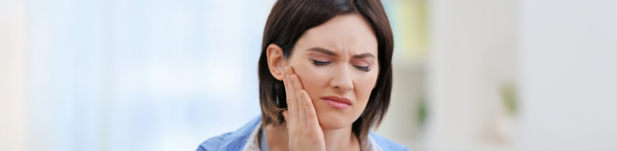 Woman holding her jaw in pain before TMJ treatment in Bullard