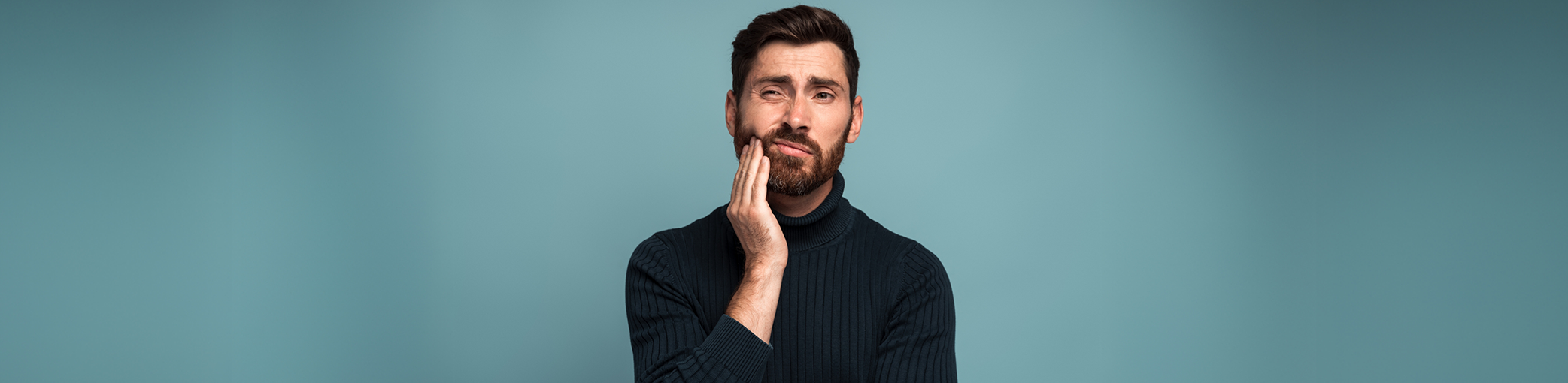 Man holding his cheek in pain before seeing an emergency dentist in Bullard