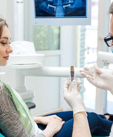 Dentist showing sample implant to patient