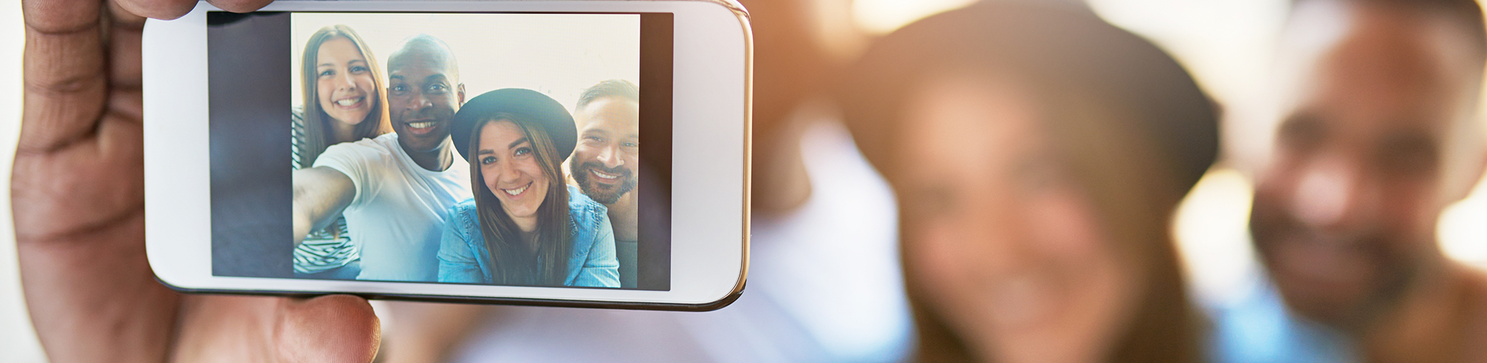 Group of smiling adults taking a selfie outdoors