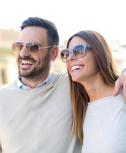 Man and woman smiling outdoors in sunglasses