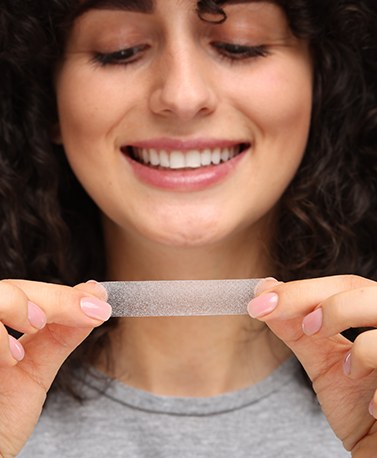 Woman holding a teeth whitening strip